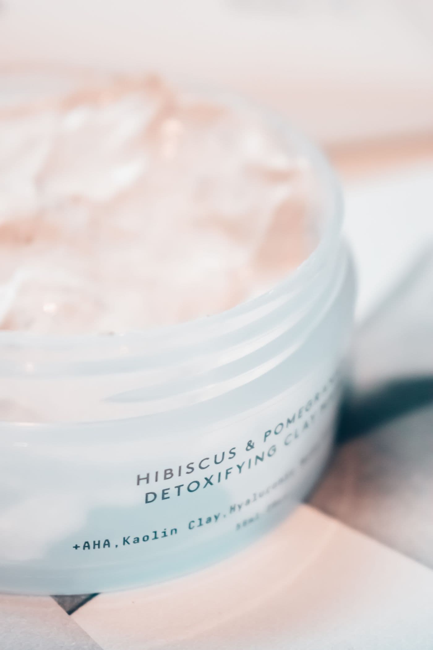 Open jar of Terra Clay Cleanser showing its whipped clay texture, next to its labeled lid.